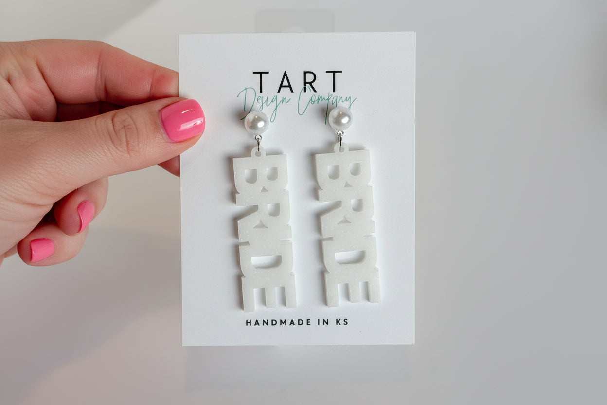 A hand holding Bride Statement earrings