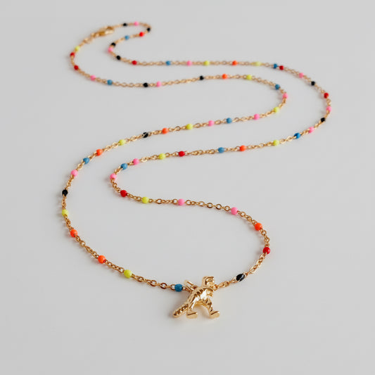 Necklace with a gold t rex charm and colorful beads on a light gray background
