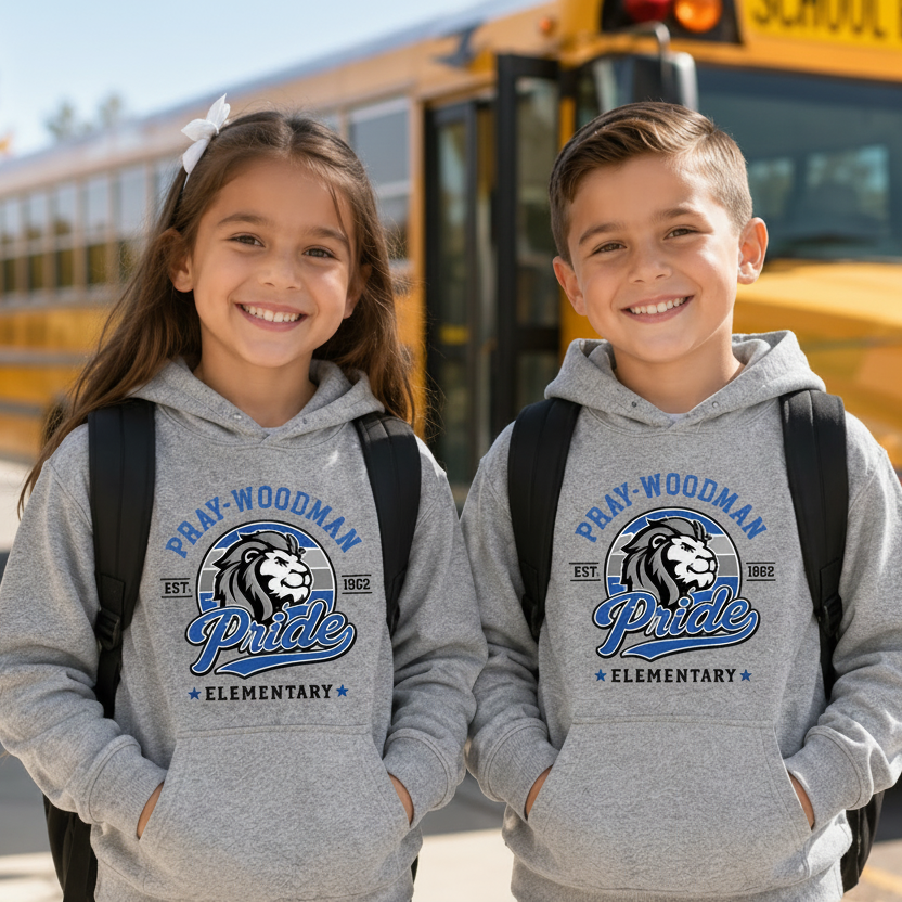 Two children wearing matching gray hoodies with a school bus graphic stand in front of a yellow school bus outdoors.