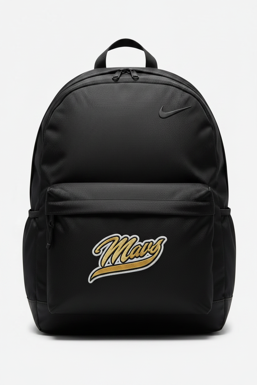 A die-cut embroidered patch featuring the word 'Mavs' in a stylized cursive script. The patch has a textured gold fill with black and white embroidered outlines, set against a gray and white checkerboard background.